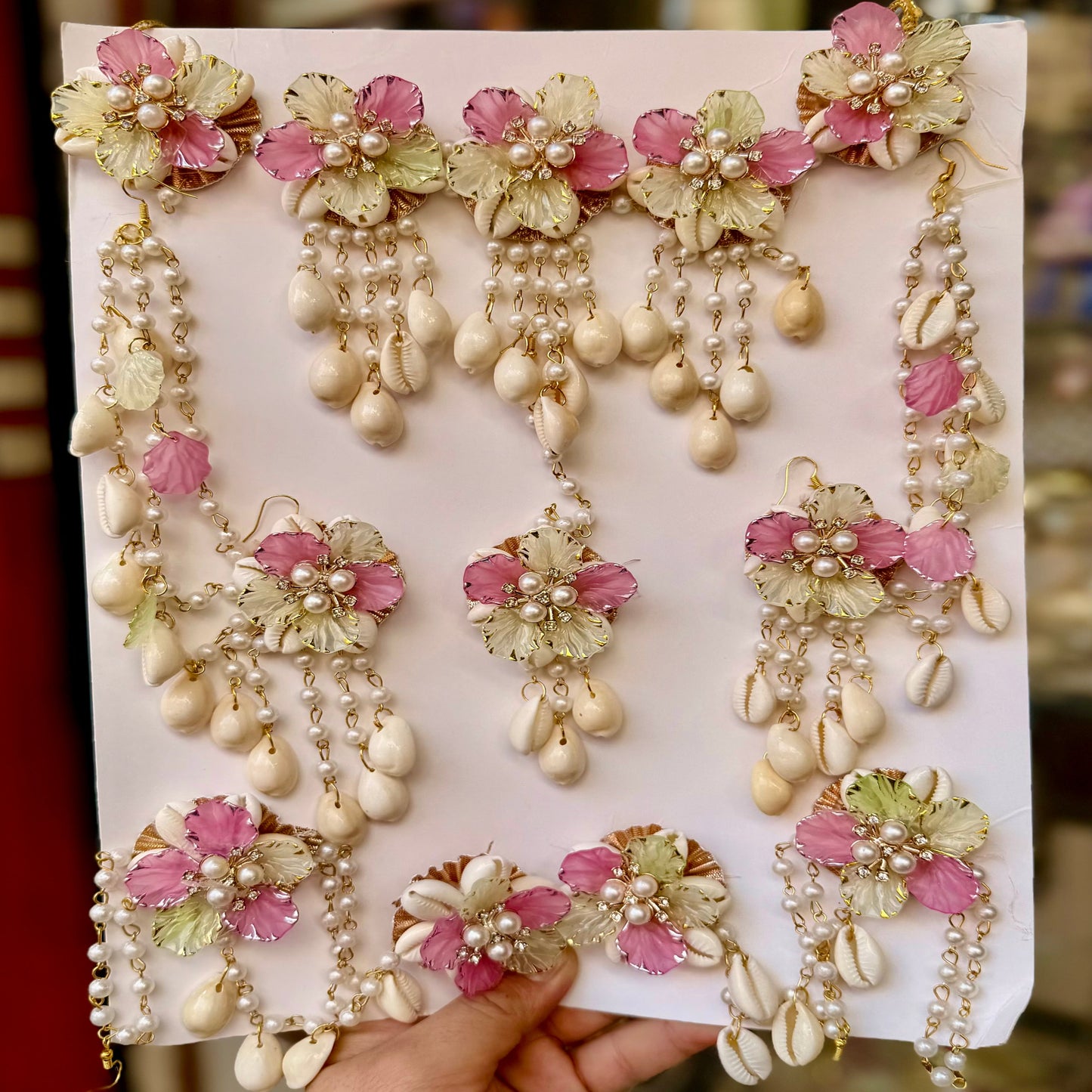 Set of decorative earrings on a white card held by a hand.